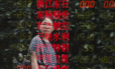A woman is reflected on an electronic board showing stock information at a brokerage house in Shanghai.