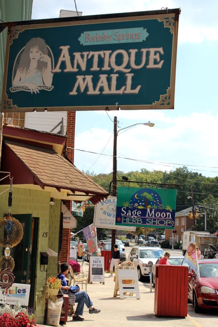A person sits outside an antique mall and an herb shop