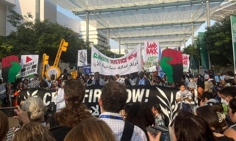 People marching at a pro-Palestinian protest at the Cop28 climate summit, with banners that read “Climate Justice Now”