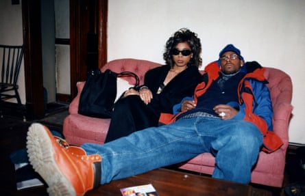 A woman in sunglasses sits on a sofa with R Kelly sprawled beside her