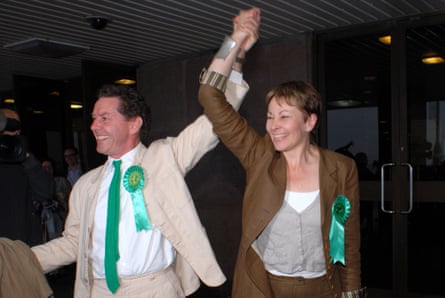 Lucas and her husband stand one hand clasped aloft in celebration.