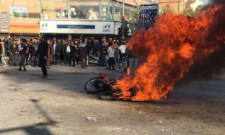 Iranian protesters gather around a burning motorcycle during a demonstration in the city of Isfahan against increased petrol prices 