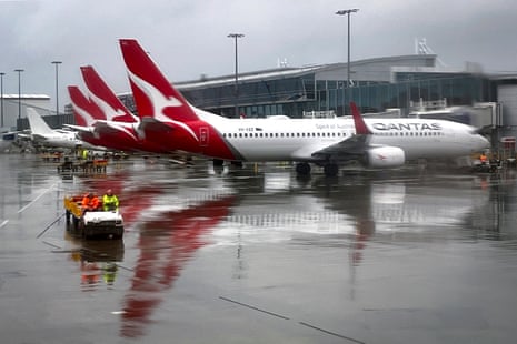 Two ground staff workers drive a vehicle past a Qantas airways Boeing 737 aircraft at the domestic terminal at Sydney airport.