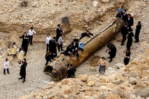 Ultra-Orthodox Jews hang around the apparent remains of a ballistic missile, after the missile and drone attack by Iran on Israel, near the southern city of Arad