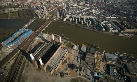 Aerial view of the power station, showing its structure with a tall chimney at each corner. The roof is missing, and the area around it appears to be barren waste ground