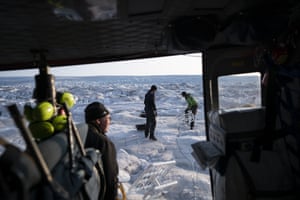 Holland, left, and NYU field safety officer, Brian Rougeux, right, are helped by pilot Martin Norregaard as they carry antennas out of a helicopter.