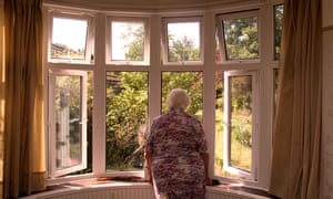 A retired woman stares out of a window