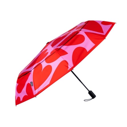 An open umbrella with a bold red and pink heart pattern, folded diagonally on display