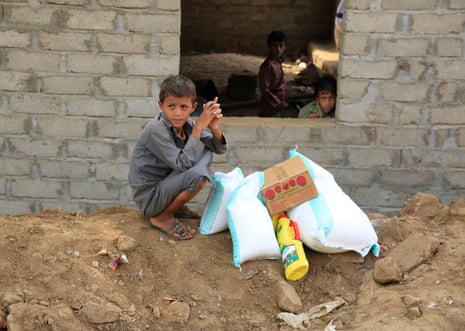 A Yemeni boy sits next to his family’s allocation of emergency food aid.