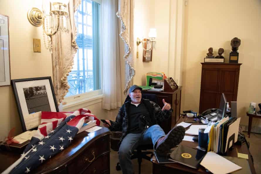 A member of the pro-Trump mob sits in Nancy Pelosi’s office in the Capitol.
