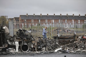 West Belfast, Northern Ireland: A man walks past a burnt out bus on the Shankill road. The scene follows another night of violence in loyalist areas that has now spread to interface areas of the peace divide