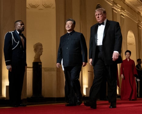 Donald Trump and Xi Jinping walk together down a red carpet at the White House