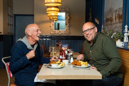 Andrew and Jonathan laughing while they eat at a restaurant table