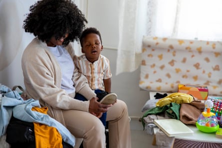 A mother putting on her young son’s shoes
