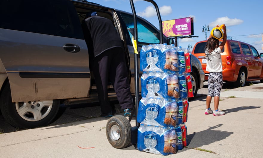 A volunteer loads bottles of water into the car of a family whose water has been shut-off.