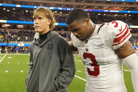 New York Giants quarterback Jaxson Dart, left, walks off the field with linebacker Abdul Carter