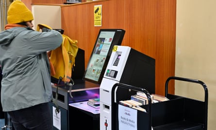 A woman with a bag of books at a self-service checkout in a library