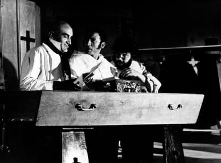 Black and white photo of three men standing behind what looks like a coffin.