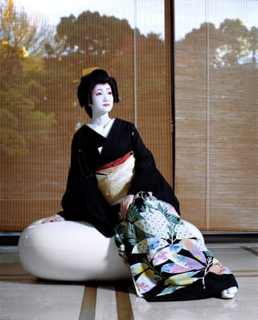 Suzume Geisha in traditional dress seen through a plate glass window