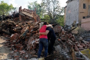 Women hug near the debris of a building that was damaged after a rocket hit the Saltivka area in Kharkiv, Ukraine