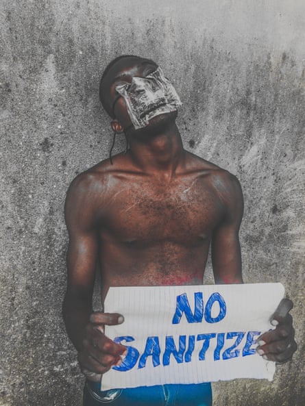 Wearing a mask made from plastic water sachets, a boy holds a sign in Orile.