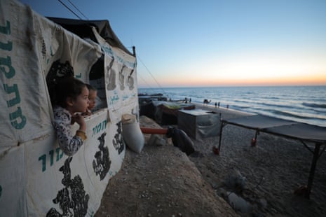 Two children look out from a makeshift tents on the coastal area in Deir al-Balah, Gaza on Thursday.