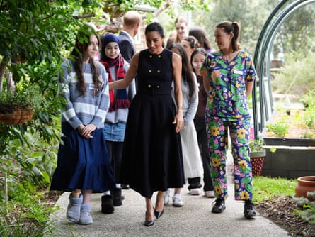 The couple walk with teenage patients and staff in a garden