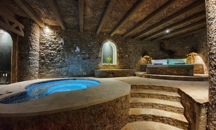 A pool inside a dark, stone building with steps and loungers
