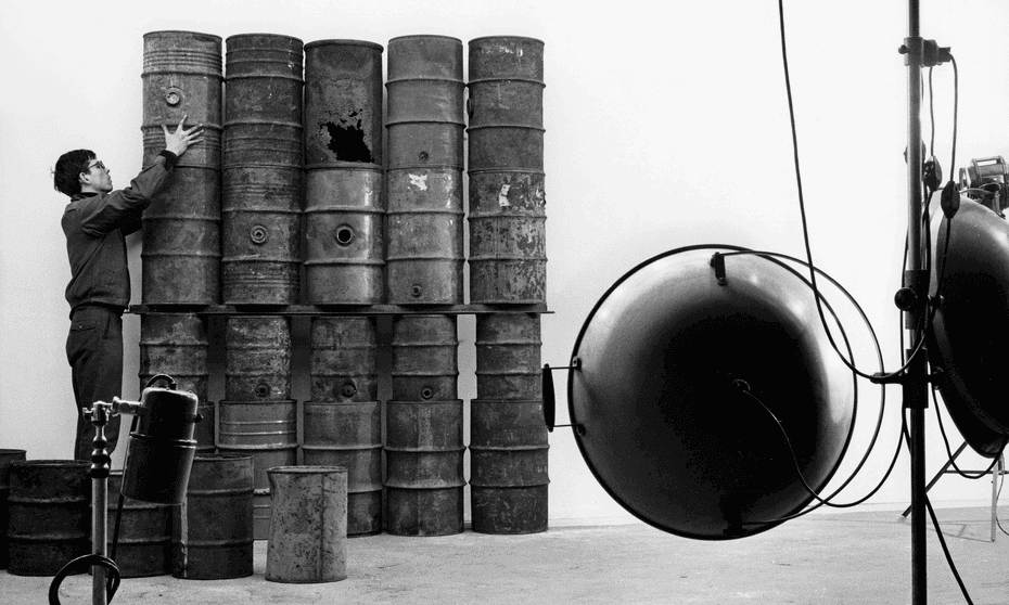 Christo during the erection of 26 Oil Barrels (1961) in the Paris studio of photographer Jean-Dominique Lajoux