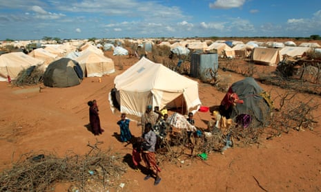 Refugees stand outside a tent at the Dadaab refugee camp