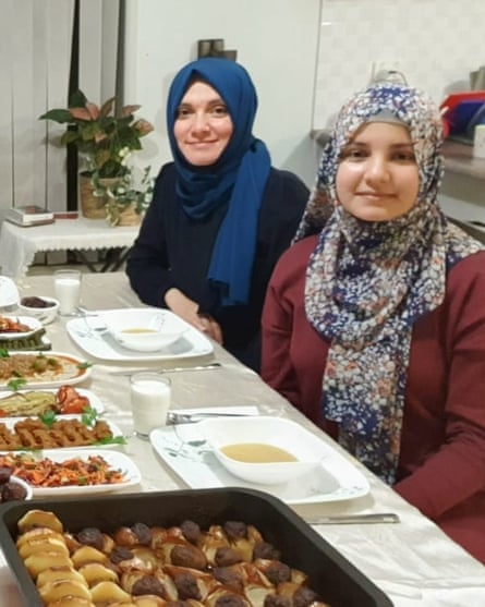 Two Muslim women in headscarves sitting at a dinner table.