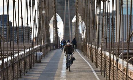 People ride bicycles on a nearly empty Brooklyn Bridge.