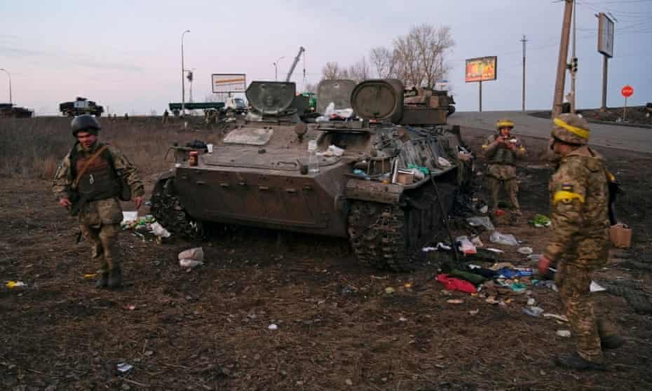 Ukrainian servicemen are seen next to a destroyed armoured vehicle, which they said belongs to the Russian army, outside Kharkiv, Ukraine, on Thursday.