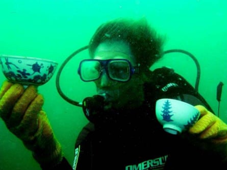 A diver holds a small porcelain dish in his hand underwater