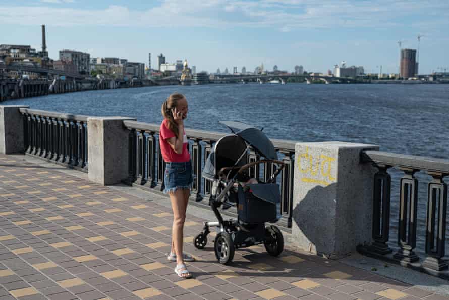 A woman talks on the phone as she stands by a baby stroller on the Dnipro river embankment on 12 June 12, 2022 in Kyiv, Ukraine.