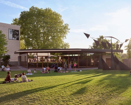 A pavilion with big glass windows, with Robert Calder artwork and people sitting on the grass