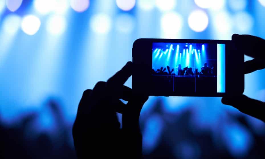 Cropped shot of a person filming their favorite band with a camera phone.