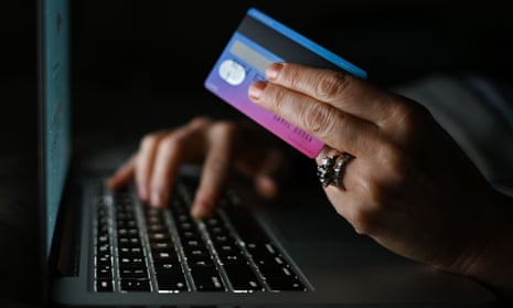A person holding a credit card while using a computer