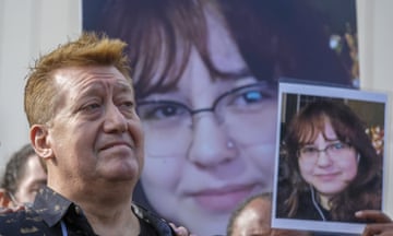A grieving middle-aged man holds a photo of his daughter.
