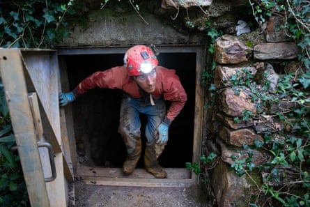 Man comes out of small, square doorway.