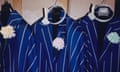 Blue and white striped blazers with carnations in their buttonholes, hanging up