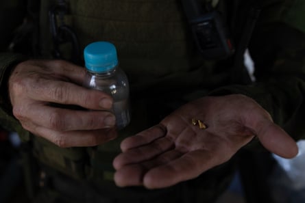 A person holding a plastic bottle in one hand a gold nugget in the other