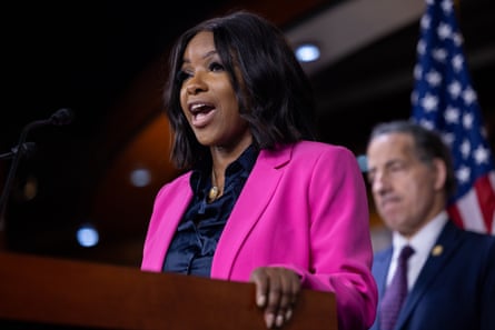 a woman in a pink blazer speaks into a microphone