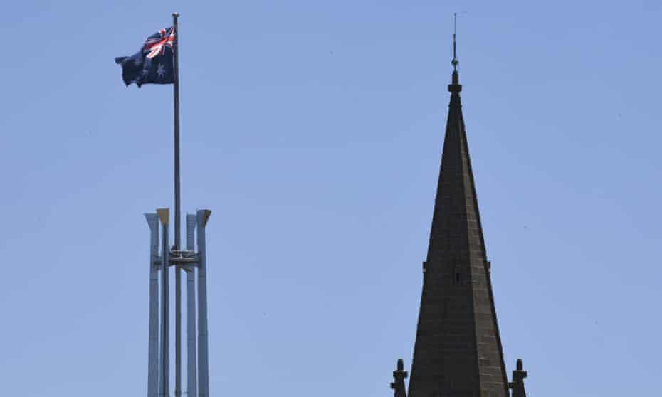 The tower of St Andrews Presbyterian Church is seen near the flag pole of the Australian Parliament House in Canberra