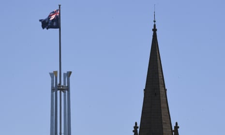 The tower of St Andrews Presbyterian Church is seen near the flag pole of the Australian Parliament House in Canberra