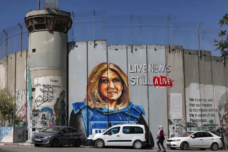 Cars are parked in front of the mural painted on the Palestinian side of Israel’s separation barrier, alongside a watch tower