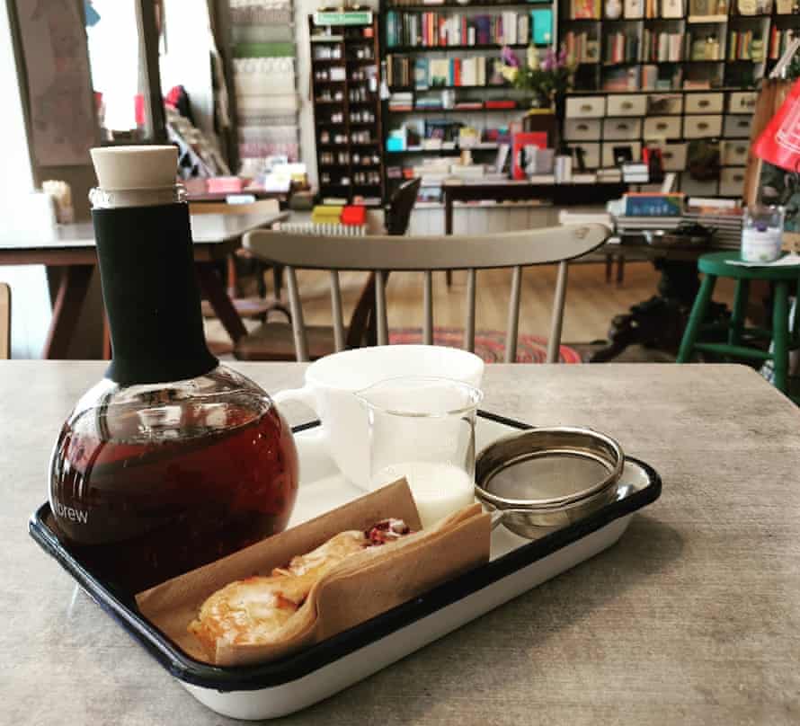 A vial of coffee and a pastry, with bookshelves in the background