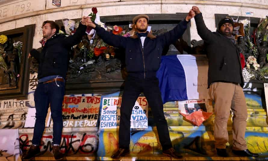 Three men are seen singing the French national anthem on the Place de la République monument.