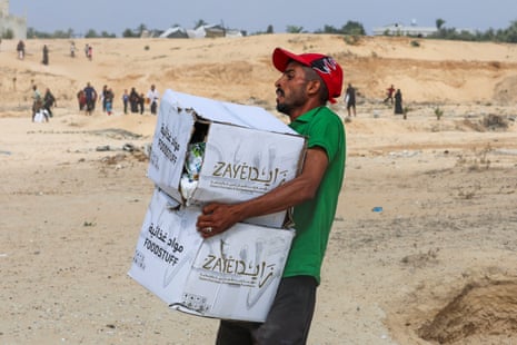 A Palestinian man carries food items collected from aid packages dropped from an airplane, amid a hunger crisis, in Deir Al-Balah, in the central Gaza Strip, earlier today.