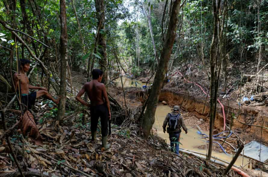 Yanomami indians follow agents of Brazil’s environmental agency during an operation against illegal gold mining on indigenous landm in Roraima state, Brazil.